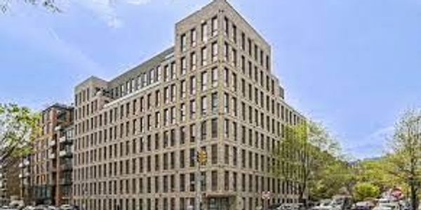 A modern multi-story apartment building at a street corner.