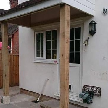New wooden porch supports on a small white house exterior.