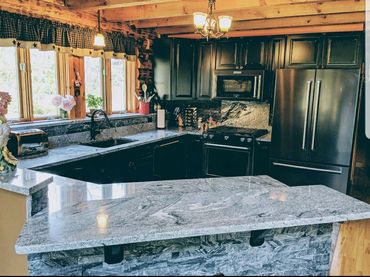 Modern rustic kitchen with granite countertops and black appliances.