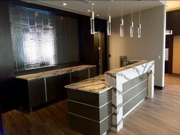 Modern reception desk with marble countertops and pendant lighting.