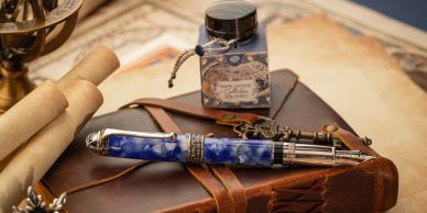 A vintage pen, ink bottle, and leather journal on a desk with scrolls.