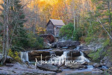 Historic watermill by a serene waterfall surrounded by autumn foliage.