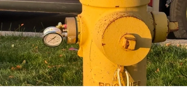 Yellow fire hydrant with a pressure gauge attached.