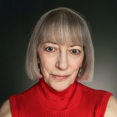 Mature woman with short gray hair wearing a red sleeveless turtleneck.