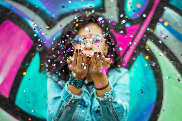 Black girl blowing confetti into the air.