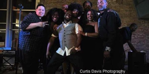 A diverse group of friends posing happily together at a night event.