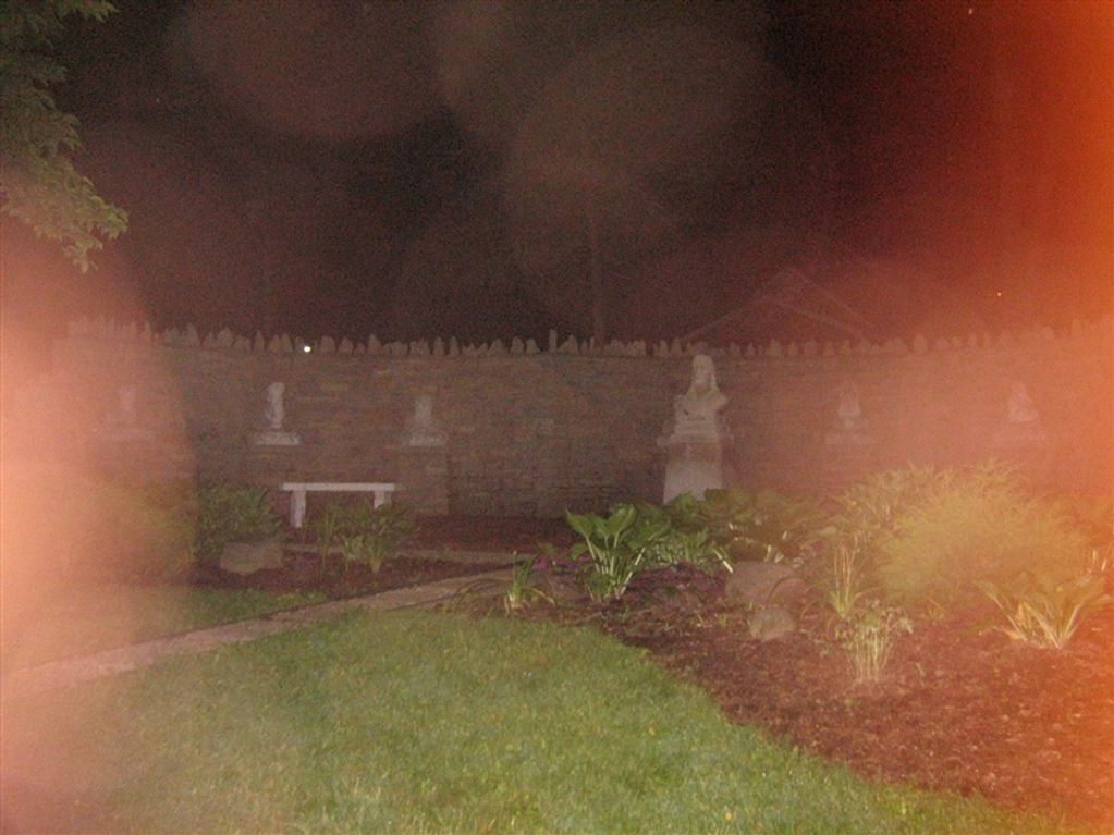 Large reddish colored orbs in front of a statue garden.