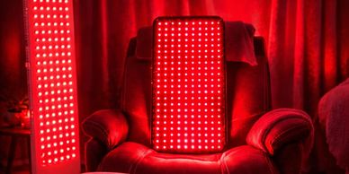 A red LED light panel on a chair with red curtains in the background.