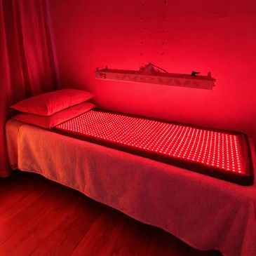A bed with red LED light therapy pads and a red-lit room.