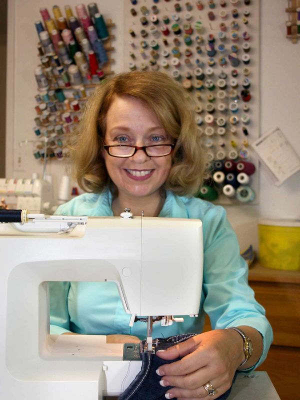 Smiling woman sewing with a machine.