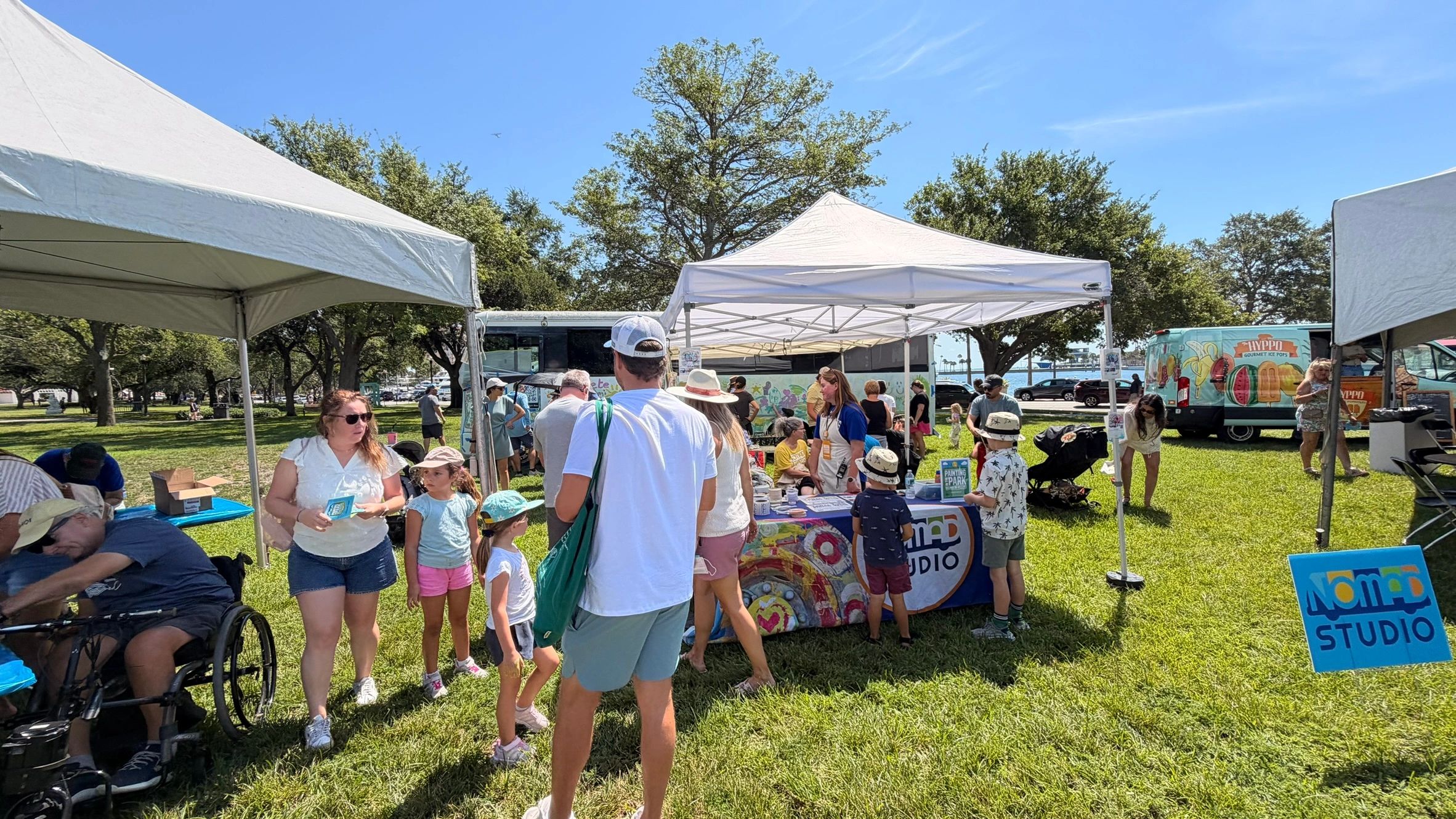 People gather at outdoor tents on a sunny day.
