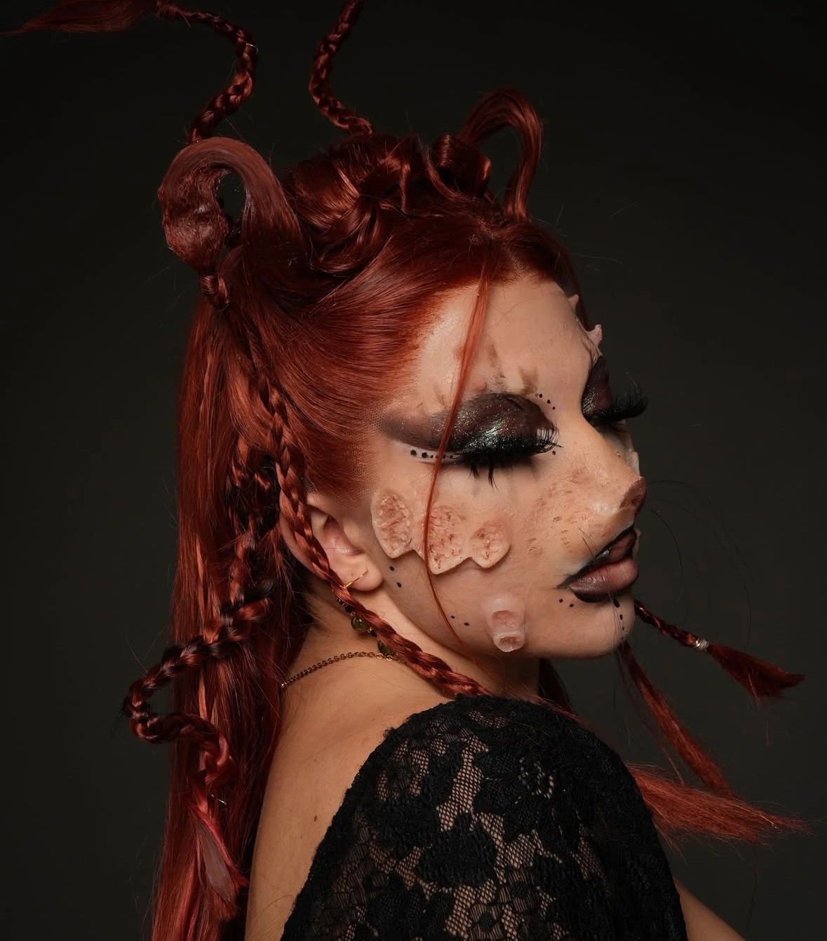 Person with elaborate red braided hair and artistic face makeup.