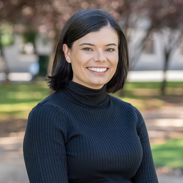 Smiling woman in a black turtleneck outdoors.