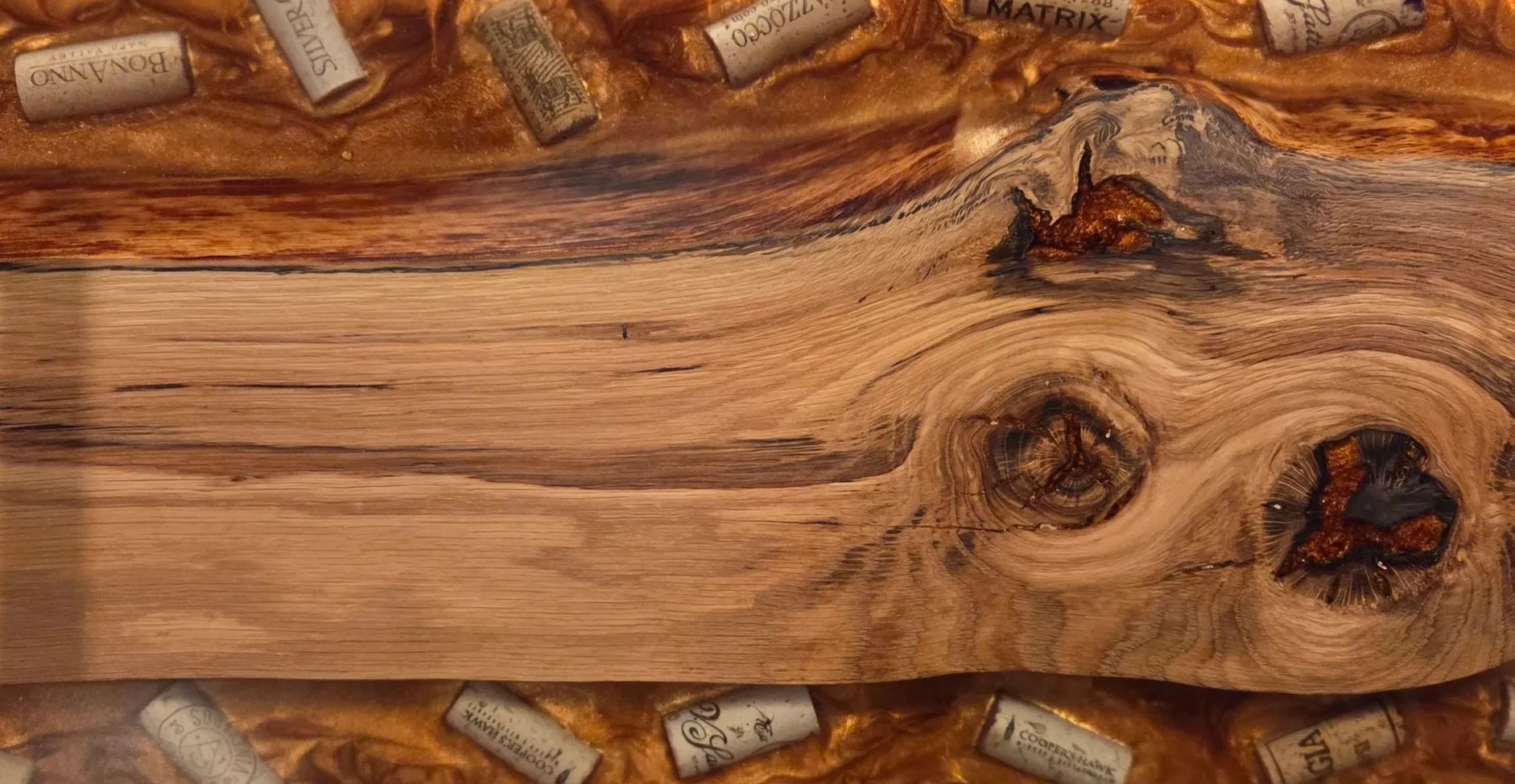 Wooden tray with embedded wine corks in amber resin and copper handles.