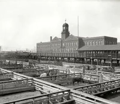 Historic livestock pens with a large brick building in the background.