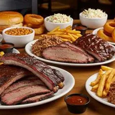 Plates of barbecue ribs, brisket, fries, and sides on a wooden table.