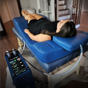 Woman lying on a blue therapy bed connected to a medical device.
