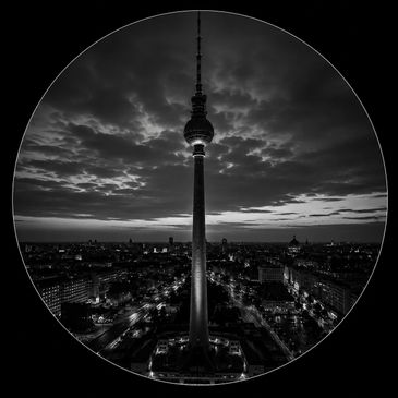 Black and white night view of a tall tower against a cloudy sky.