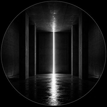 A narrow vertical light cuts through a dark, empty concrete room.