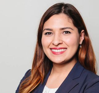 Professional woman smiling in business attire against a plain background.