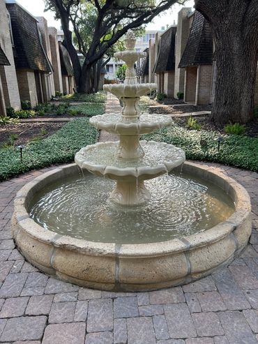 A three-tiered water fountain in a peaceful garden courtyard.