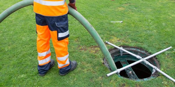 Man in safety gear pumping septic tank
