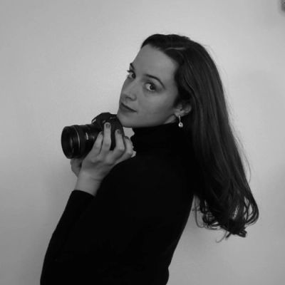 Woman holding a camera, looking over her shoulder in a black and white photo.