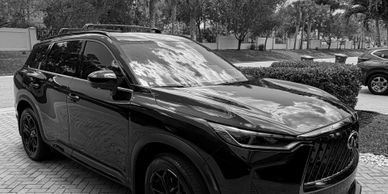 Black luxury SUV parked on a driveway with reflections on its surface.