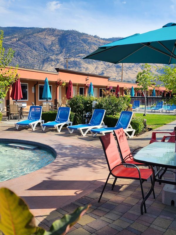 Pool area with lounge chairs and umbrellas under blue sky.