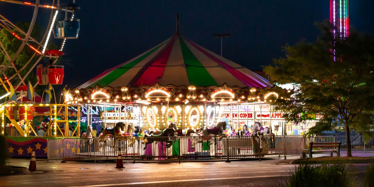 A brightly lit carousel at a nighttime carnival.