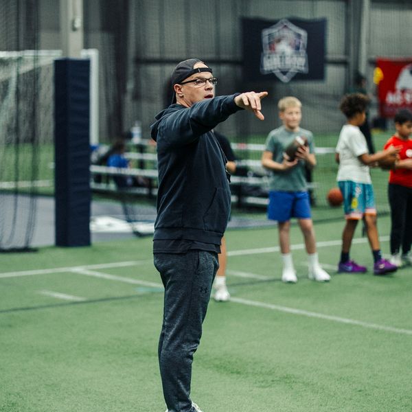 Coach giving instructions to kids on an indoor sports field.