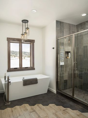 Modern bathroom with a white bathtub and glass shower enclosure.