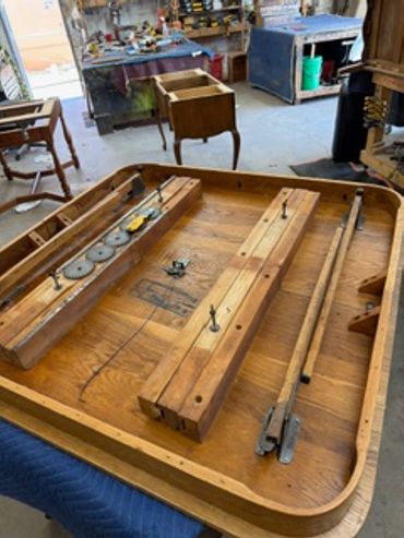 Disassembled wooden table with tools in a workshop.