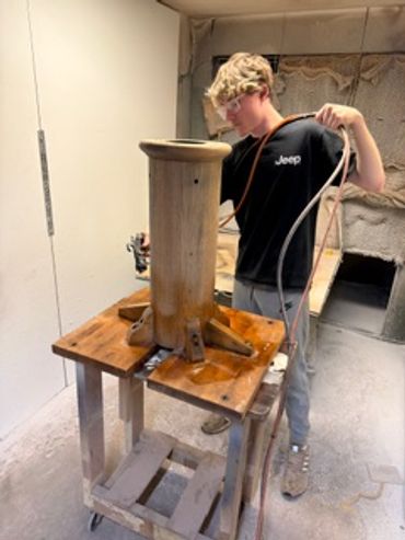 Person working with a wooden structure in a workshop.
