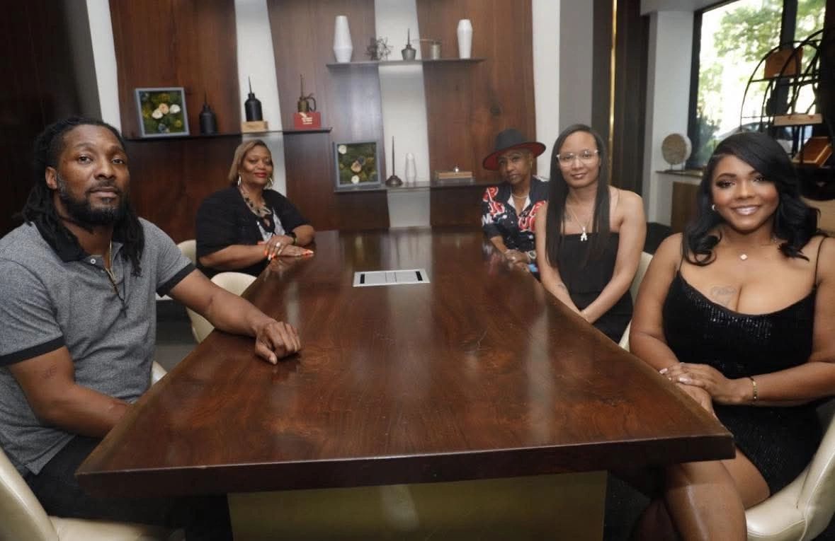 Five people sitting around a large wooden conference table indoors.