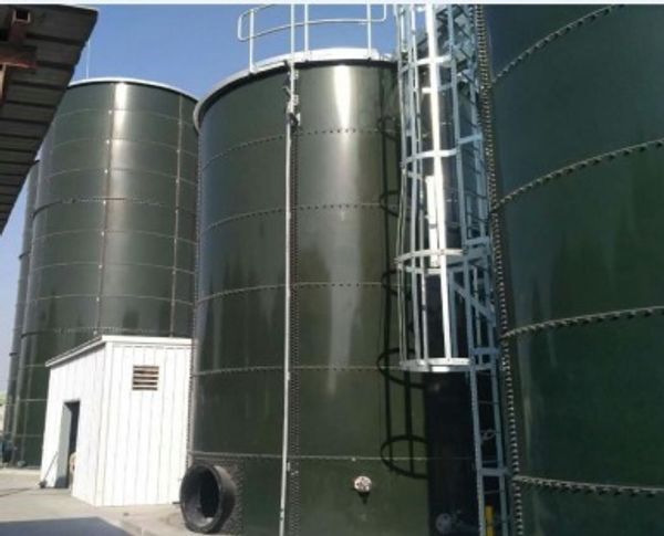 Three large industrial storage tanks with a small white building nearby.
