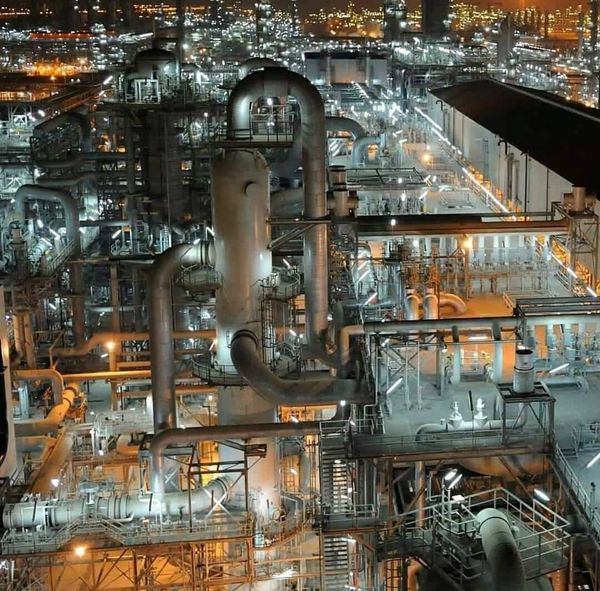 Night view of an industrial refinery with numerous pipes and lights.