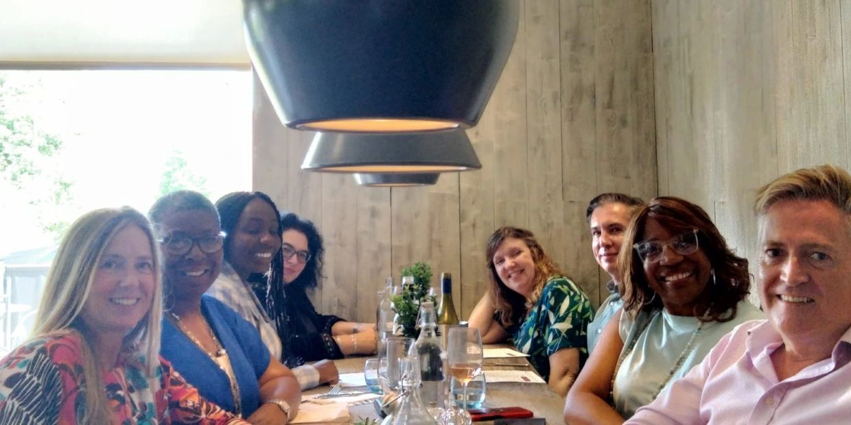Group of people smiling at a dining table in a cozy restaurant.