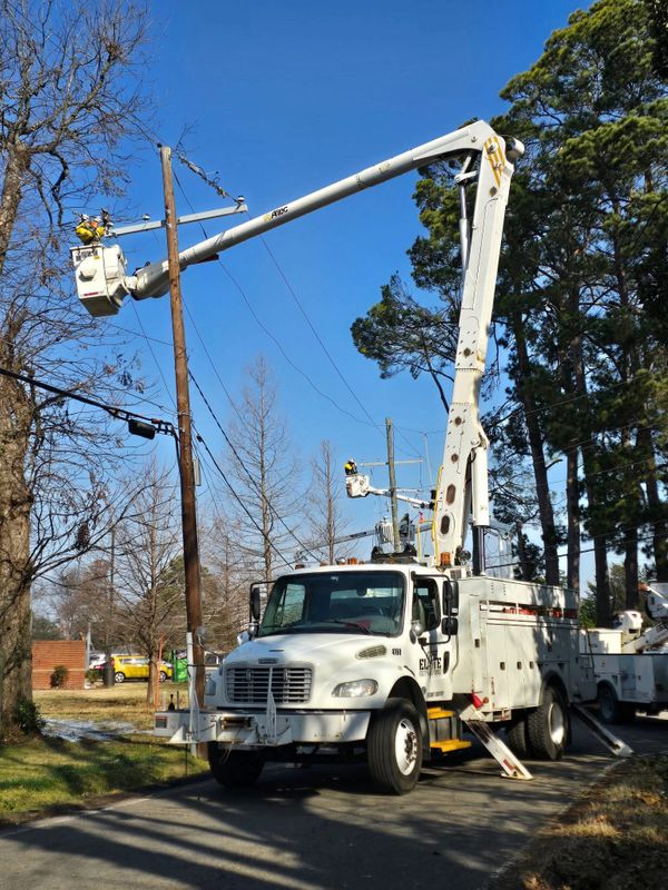 Utility truck with bucket lift repairing power lines on a clear day.