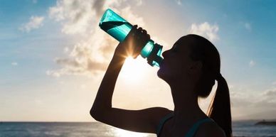 Silhouette of girl drinking water from a water bottle at the beach. 