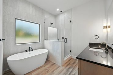 Modern bathroom with freestanding tub and glass shower enclosure.