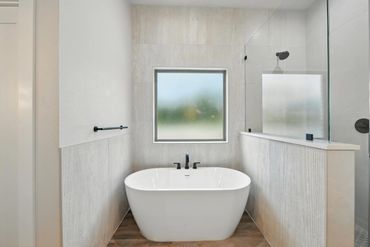 Modern bathroom with freestanding tub and frosted window.