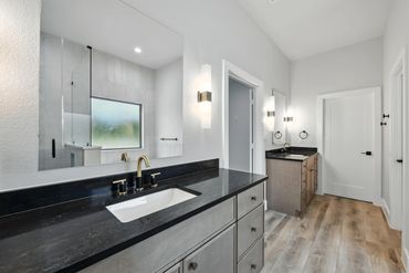 Modern bathroom with black countertops and wood flooring.