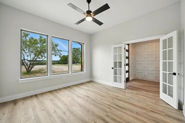 Bright room with large windows, ceiling fan, and French doors.