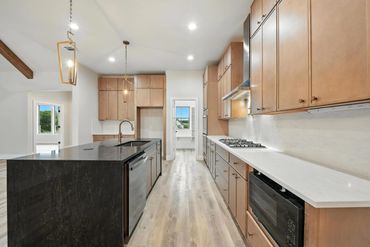 Modern kitchen with wood cabinets, black island, and stainless steel appliances.