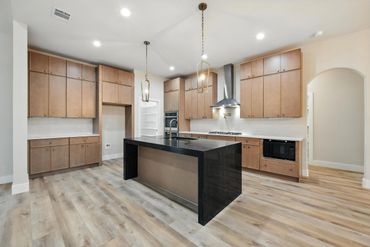 Modern kitchen with wooden cabinets and a black island.