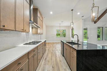 Modern kitchen with wooden cabinets, black granite island, and large windows.
