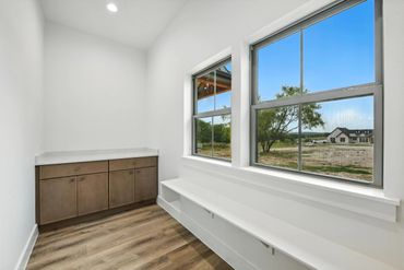 Bright room with large windows, wooden cabinets, and a white bench with cubbies.