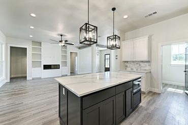 Modern kitchen and living area with pendant lights and sleek island.
