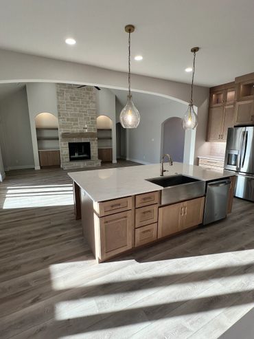Modern kitchen with island and stone fireplace in living area.